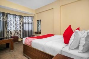 大吉岭OYO Hill Grand Himalaya的一间卧室配有一张带红色枕头的大床