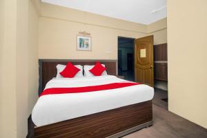 大吉岭OYO Hill Grand Himalaya的一间卧室配有一张带红色枕头的大床