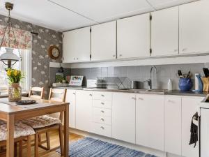 乌洛夫斯特伦Holiday Home Skjutsmåla - B的厨房配有白色橱柜和木桌