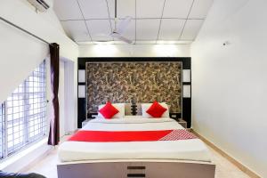 苏拉特OYO Nova Dumas Homestay的一间卧室配有一张带红色枕头的大床