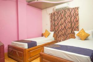 Alīpur DuārOYO Hotel Chitra的配有粉红色墙壁的客房内的两张床