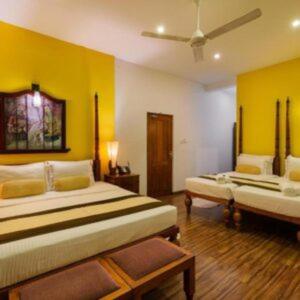 波隆纳鲁沃Suneetha Hotel的一间卧室设有两张床,拥有黄色的墙壁