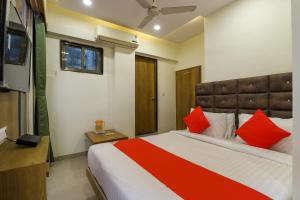 艾哈迈达巴德OYO Hotel Shubham Inn的一间卧室配有一张带红色枕头的大床