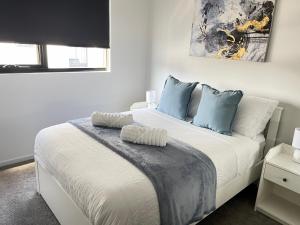 TuggeranongBlackdiamond 504 - Beautiful, modern apartment - 2BdR, 2BthR的卧室配有带蓝色枕头的大型白色床