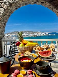 米克诺斯城Yalos Hotel Sunset view Mykonos town private rooms的一张桌子,上面有食物,享有海景