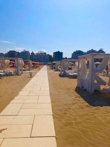 里米尼Hotel Alessi** Rimini的沙滩上设有桌椅
