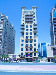 迪拜Palette Royal Reflections Hotel and Spa Dubai的一座高大的白色建筑,前面有汽车停放