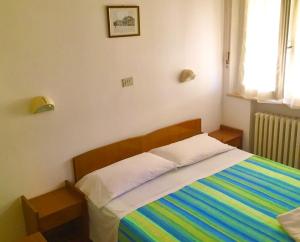 里米尼Hotel Alessi** Rimini的一间卧室配有一张带彩色条纹毯子的床