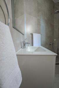 萨兰达Ladi Elegant Suites near the Sea的白色的浴室设有水槽和镜子