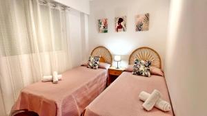 洛斯马蒂雷斯VORA GANDIA BEACH - Alquiler Familias的配有粉红色床单的客房内的两张床