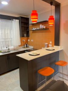坎帕拉Athena Apartments的一个带2把橙色椅子的岛屿的厨房