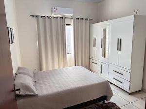 锡诺普Casa bem localizado em Sinop的一间白色卧室,配有一张床和一个梳妆台