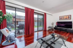 NarrabundahAwesome family House & Studio的客厅配有红色窗帘和电视