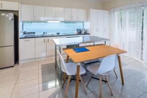 布里斯班Modern 2BR With Deck的厨房配有木桌和白色橱柜。