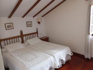 桑提亚纳德玛Montañes的一间卧室配有一张带白色床单的床和一扇窗户。