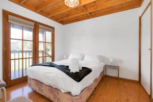 Malua BayMuwarra Cottage Malua Bay的一间卧室配有一张带白色床单的床和一扇窗户。