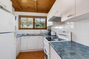 Malua BayMuwarra Cottage Malua Bay的一间厨房,配有白色家电和木制天花板