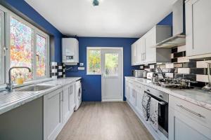 布里斯托Spacious Luxury Garden House Free Parking的一间拥有蓝色墙壁和白色橱柜的大厨房