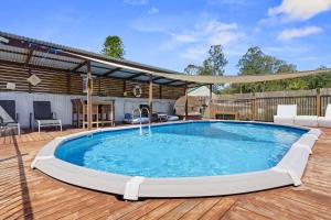KarraganbahLake House Tuggerawong NSW的木制甲板上的大型游泳池,设有天井