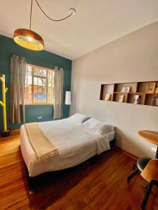 波哥大Bendito Hostels的一间卧室配有一张床、一张桌子和一个窗户。