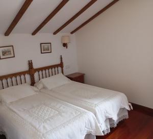 桑提亚纳德玛Montañes的一间卧室配有一张带白色床单的大床