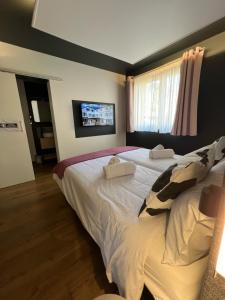 比桑Hôtel Restaurant & Spa du Tremplin的一间卧室设有两张床,墙上配有电视。