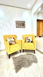 诺阿瑟Taj nouaceur aéroport Mohamed V的客厅里设有两把黄色椅子和一张地毯