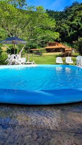 康赛瓦托利亚Hotel Fazenda Monteiro的蓝色游泳池配有椅子和遮阳伞