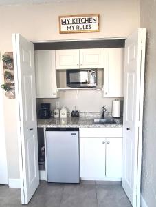 萨拉索塔Studio University Pines at Sarasota的厨房配有白色橱柜、水槽和微波炉
