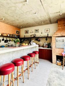 明德卢Casa de Poço Guest House and Gallery的厨房里设有红色凳子的酒吧