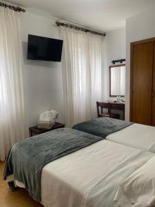 巴约讷Hotel Carabela La Pinta的一间卧室设有两张床,墙上配有电视。