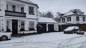 斯劳Sussex Lodge Guest House的一条有两栋房子和一辆汽车的雪覆盖的街道