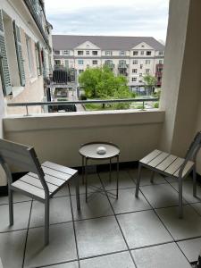 莱茵河畔路德维希港Living Apartments Ludwigshafen的阳台配有两把椅子和一张桌子,还有一个窗户。