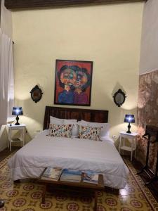 圣多明各Boutique Colonial House Hotel的卧室配有一张床,墙上挂有绘画作品
