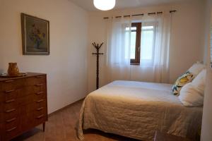 渥尔特拉Podere Santa Renata的一间卧室配有一张床、一个梳妆台和一扇窗户。