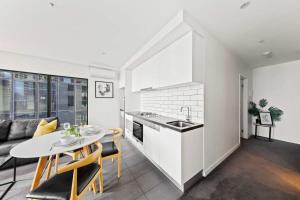 墨尔本A Modern & Spacious 2BR Apt City Views Southbank的厨房以及带桌椅的起居室。