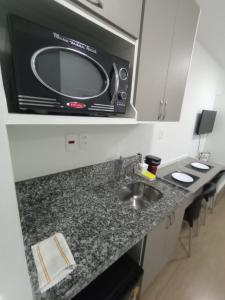 圣保罗Studio completo ao lado do metrô Brás的厨房柜台上方的微波炉配有水槽