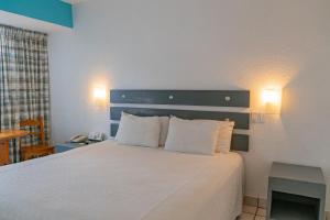 拉巴斯La Concha Beach Hotel & Club的卧室配有白色的床和2个枕头