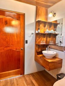 蒙泰韦尔德哥斯达黎加Hotel Trópico Monteverde的一间带水槽和木门的浴室
