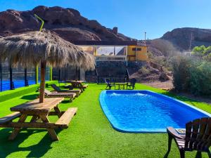 塔尔塔尔Cabañas Caleta Hueso的一个带野餐桌和稻草伞的游泳池