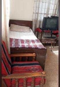 安曼Al Amawi Hostel的一间带两张床、一张沙发和一台电视的卧室