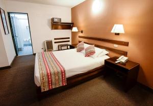 库斯科Hotel Raymi的酒店客房配有一张床和电话