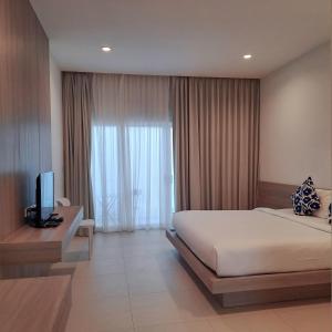 湄南海滩Baanfah Resort Samui的一间卧室设有一张床、一台电视和一个窗口。