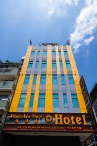 胡志明市Khách sạn Phước Lộc Thọ 2 - 福禄寿的一座高大的黄色建筑,上面有酒店标志