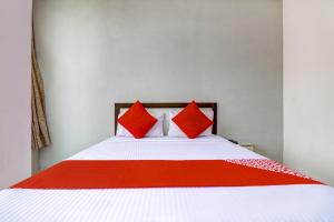 法里达巴德OYO Siya Residency的一间卧室配有一张带红色枕头的床