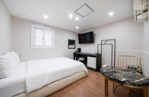 釜山Gwanganli Calm Rest Hotel的白色卧室配有床和桌子