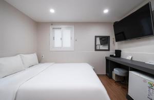 釜山Gwanganli Calm Rest Hotel的卧室配有白色的床和平面电视。