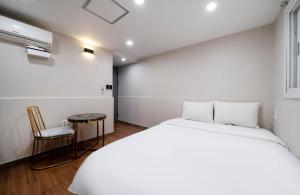 釜山Gwanganli Calm Rest Hotel的白色卧室配有床和椅子