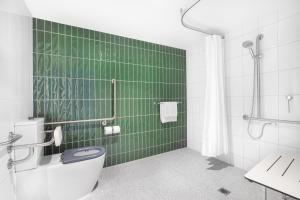 丹德农Holiday Inn Dandenong, an IHG Hotel的绿色瓷砖浴室设有卫生间和淋浴。