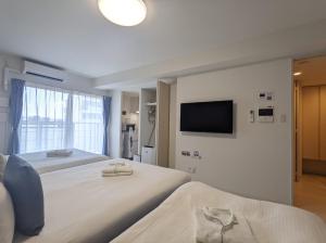 大阪ESLEAD HOTEL Osaka Nipponbashi的一间卧室配有两张床和一台平面电视